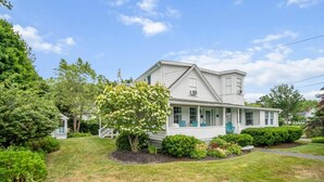 A two-story house with a porch, surrounded by well-maintained lawns and trees.