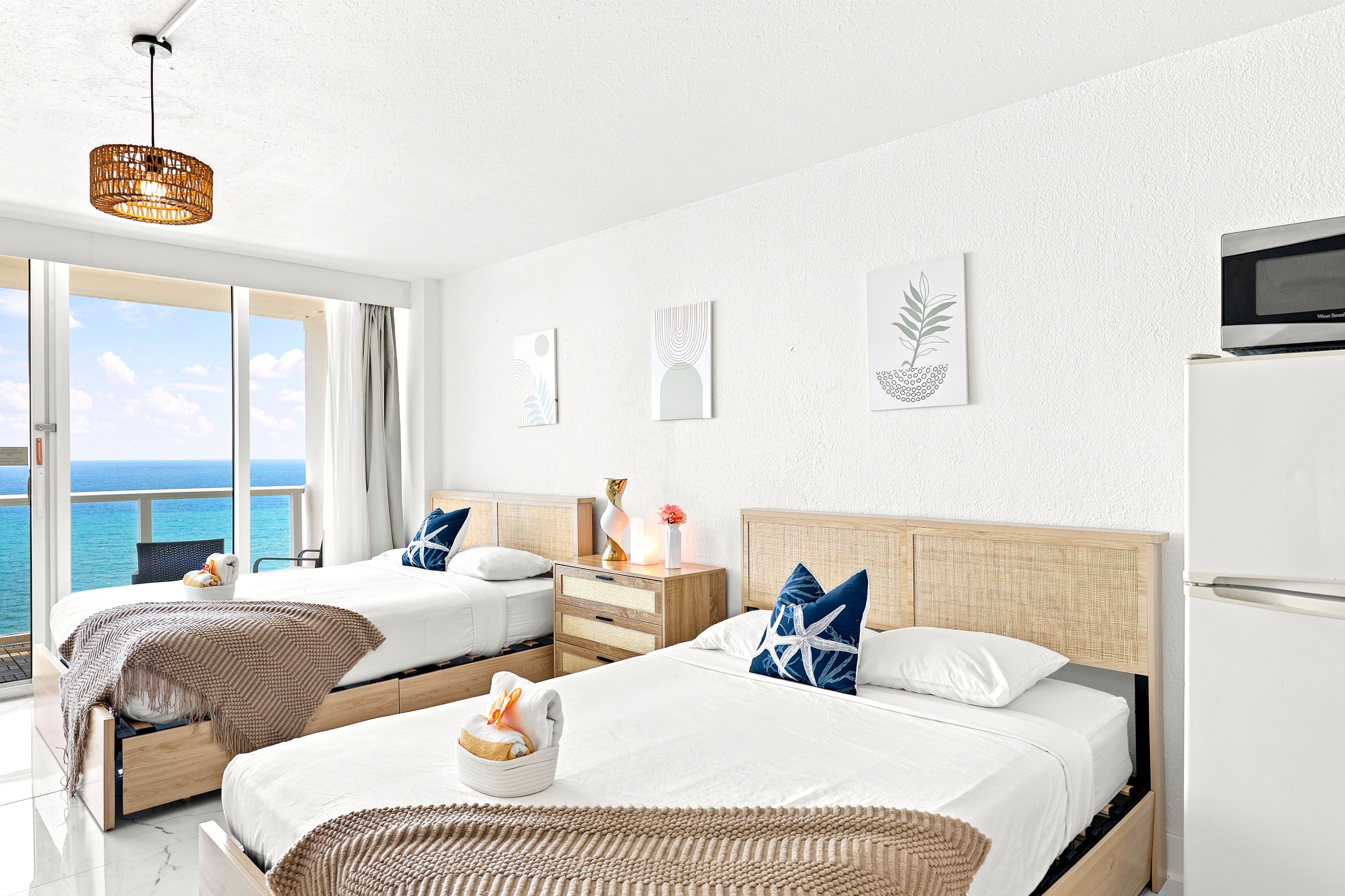A hotel room with two beds, a view of the sea, and a modern design.