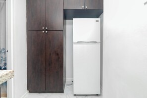 A kitchen with a dark wooden cabinet and a white refrigerator. - Boutique Apartments Castle Beach (Miami Beach)