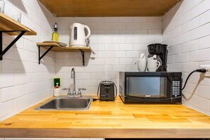 Eine kompakte Küche mit Spüle, Toaster, Mikrowelle, Wasserkocher und Kaffeemaschine auf einer Holzauskład.