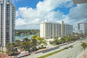 A high-rise building with a marina and a road with vehicles. - Boutique Apartments Castle Beach (Miami Beach)