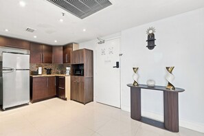 A modern kitchen with a refrigerator, microwave, and wooden cabinets. - Boutique Apartments Castle Beach (Miami Beach)
