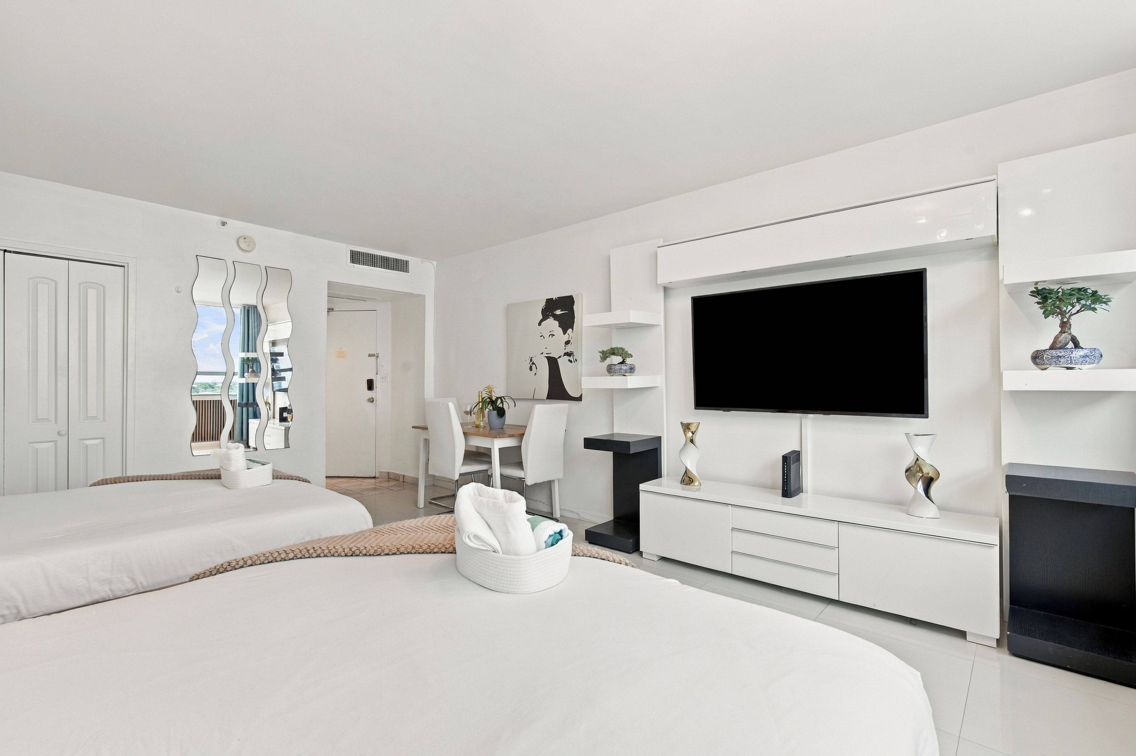 Une chambre d’hôtel moderne avec deux lits, un coin repas, une télévision et un petit balcon.