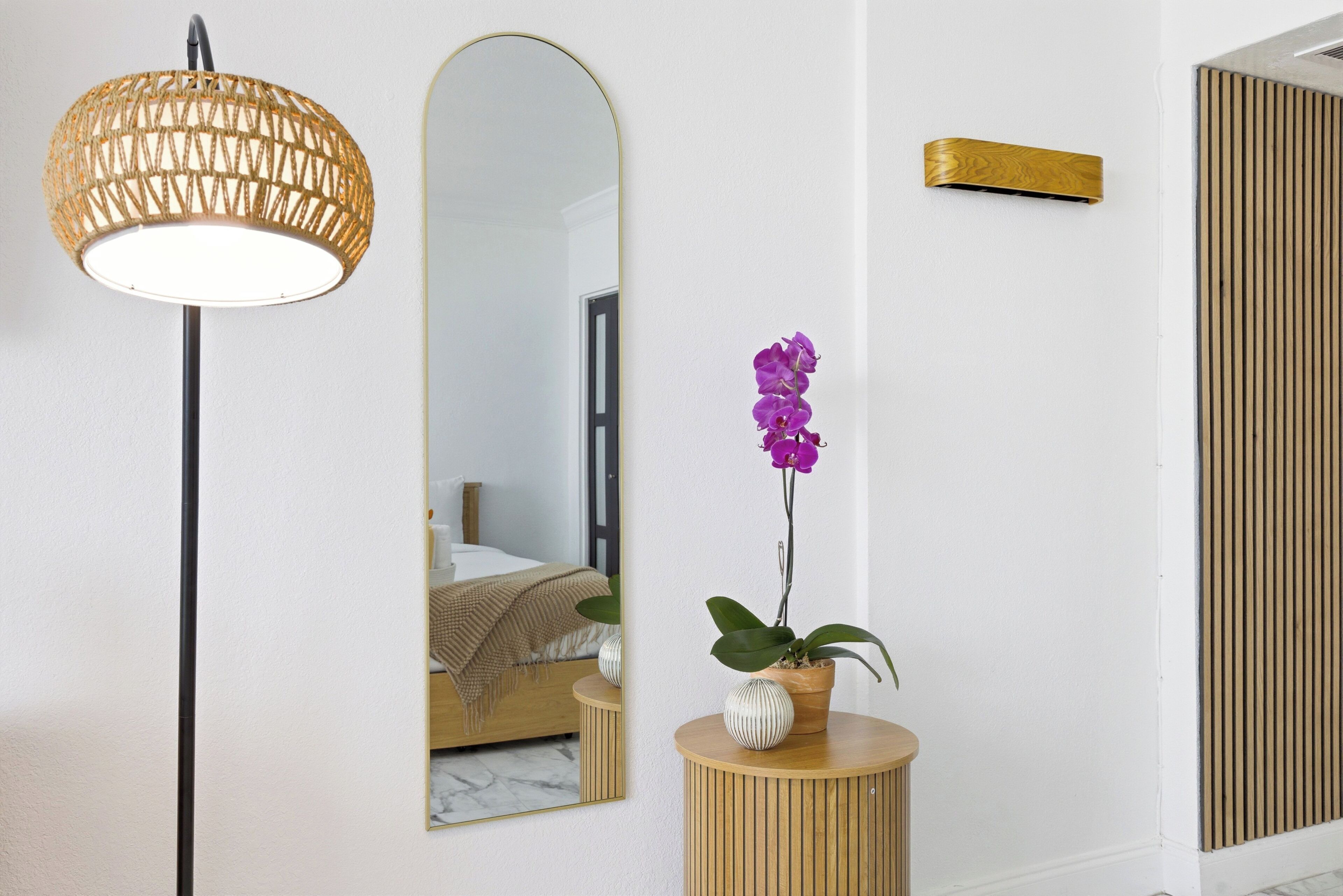 A room with a mirror, a hanging lamp, a potted orchid, and a wooden panel.