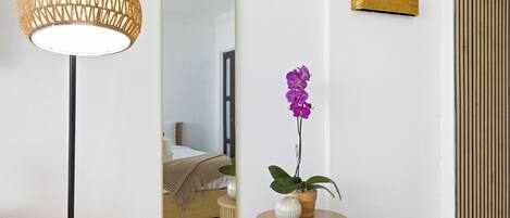 Une pièce avec un miroir, une lampe suspendue, une orchidée en pot et un panneau en bois.