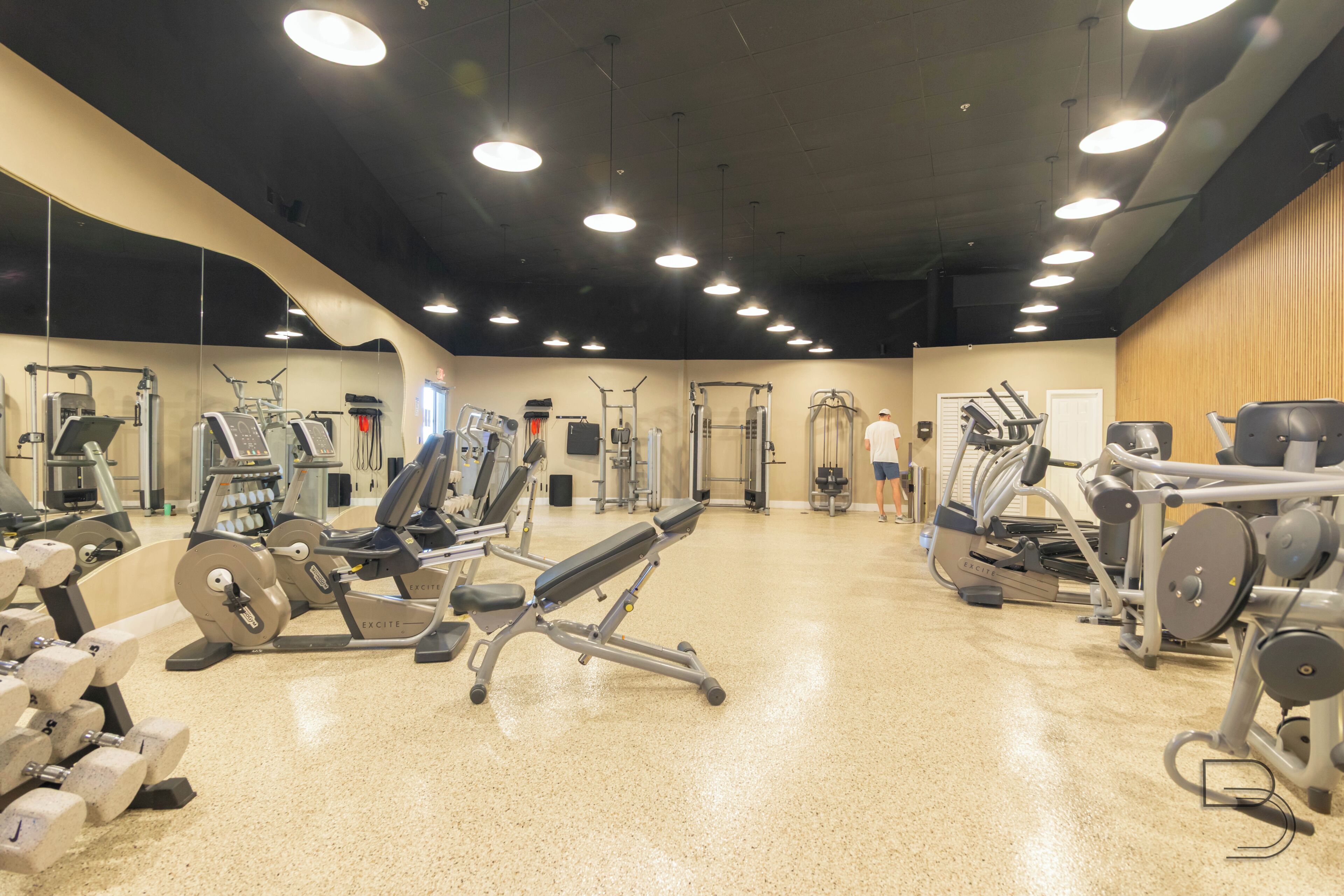 Un gimnasio con diversos equipos de ejercicio, incluyendo cintas de correr, máquinas de pesas y pesas libres.