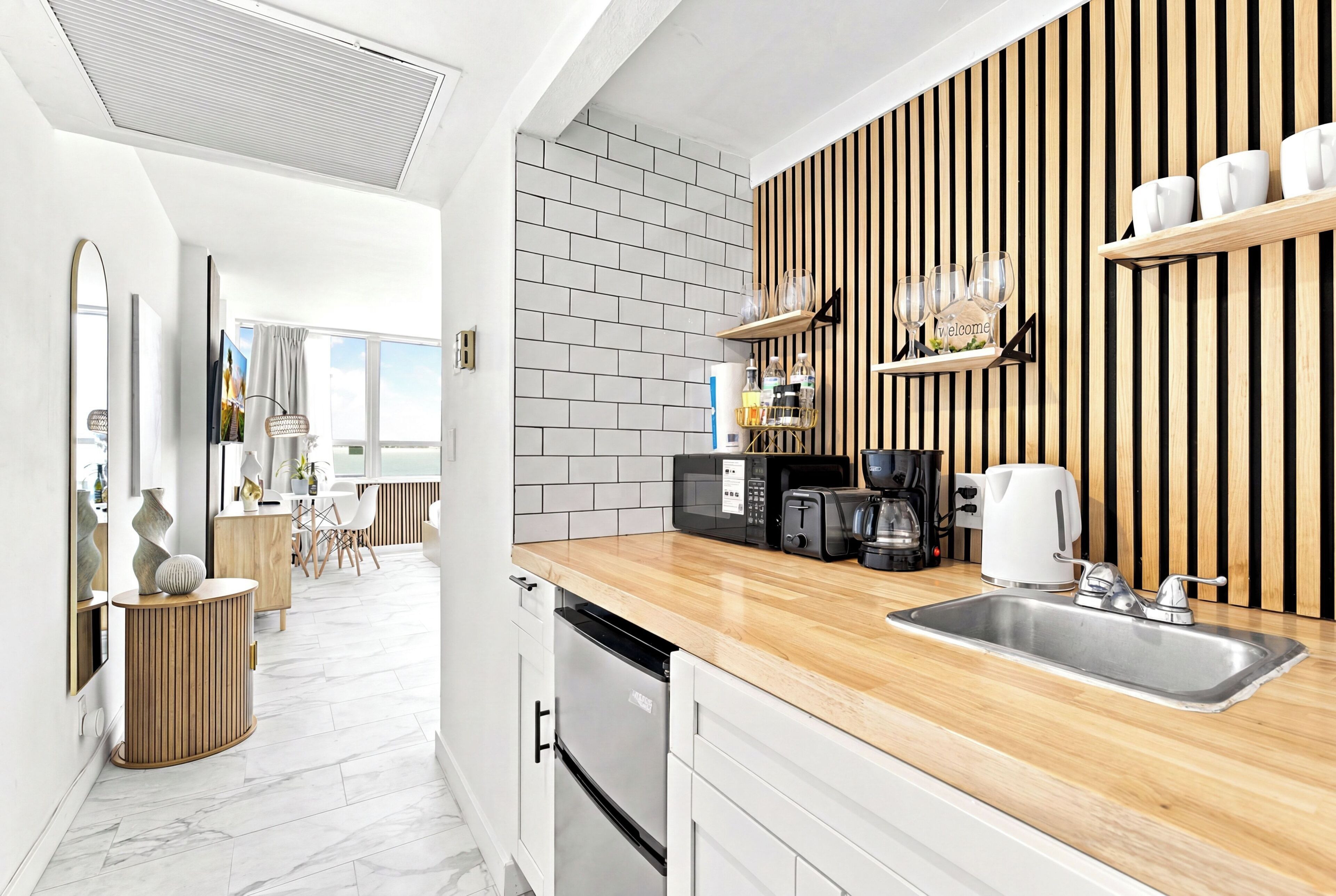 Una cocina moderna con encimera de madera, pileta de acero inoxidable y microondas.