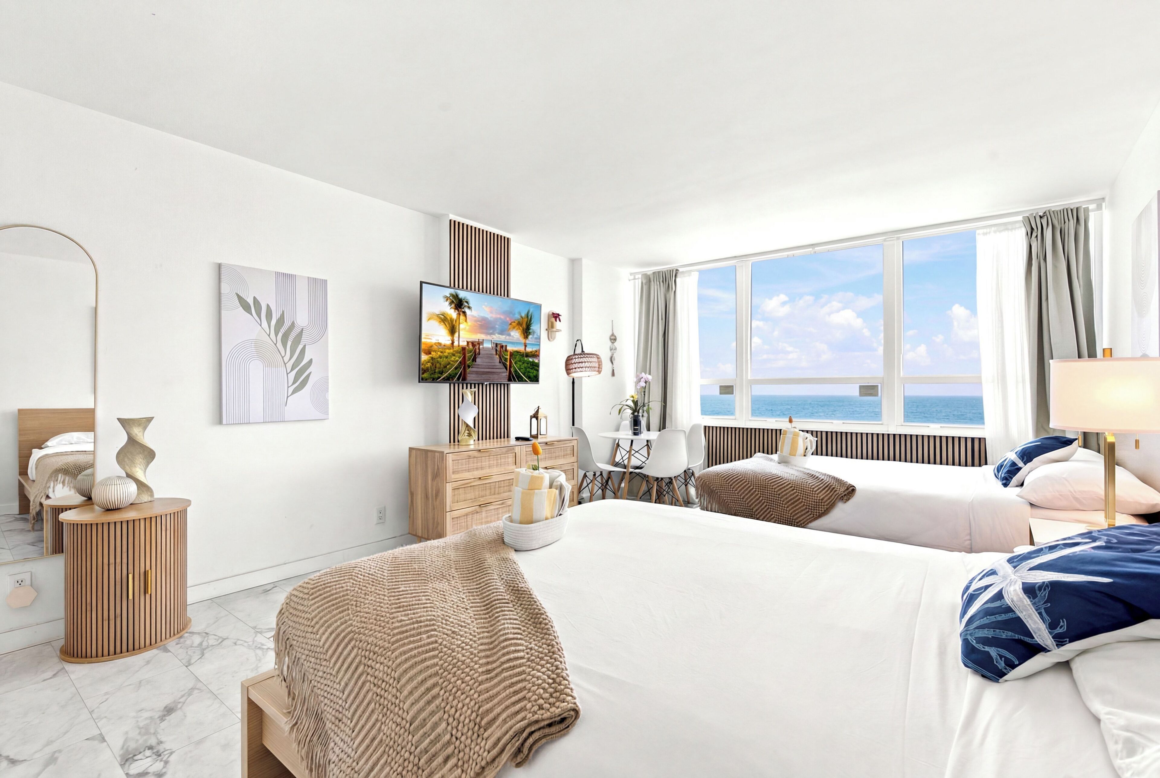 Une chambre d’hôtel avec un grand lit, un bureau, une télévision et une vue sur la mer.