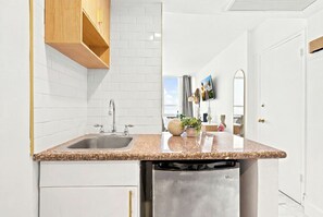 Una cocina moderna con encimera de granito, pileta de acero inoxidable y muebles de madera.