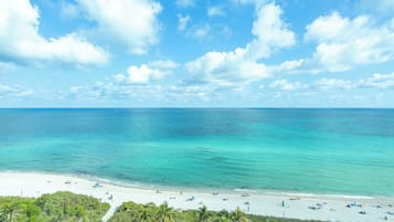 A beach with clear turquoise water, white sand, and palm trees.