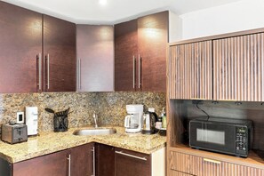 A kitchen with granite countertops, a coffee maker, a toaster, and a microwave. - Boutique Apartments Castle Beach (Miami Beach)