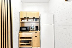 A compact kitchenette with a microwave, coffee maker, and storage cabinets. - Boutique Apartments Castle Beach (Miami Beach)
