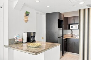 A modern kitchen with a built-in refrigerator, a coffee maker, and a microwave. - Boutique Apartments Castle Beach (Miami Beach)