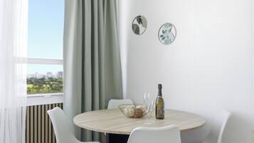 Un comedor moderno con una mesa redonda, sillas blancas, una botella de vino y platos decorativos en la pared.