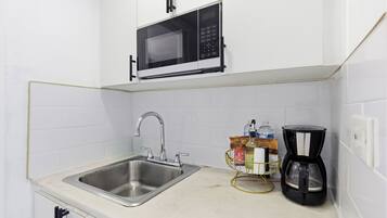 Cozinha equipada com pia de aço inoxidável, micro-ondas e máquina de café.