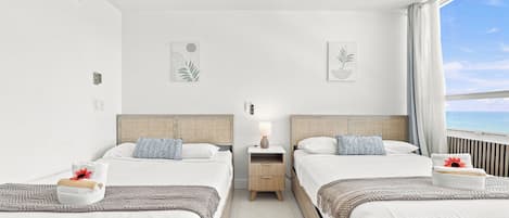 A hotel room with two beds, a nightstand, a lamp, and artwork on the walls.