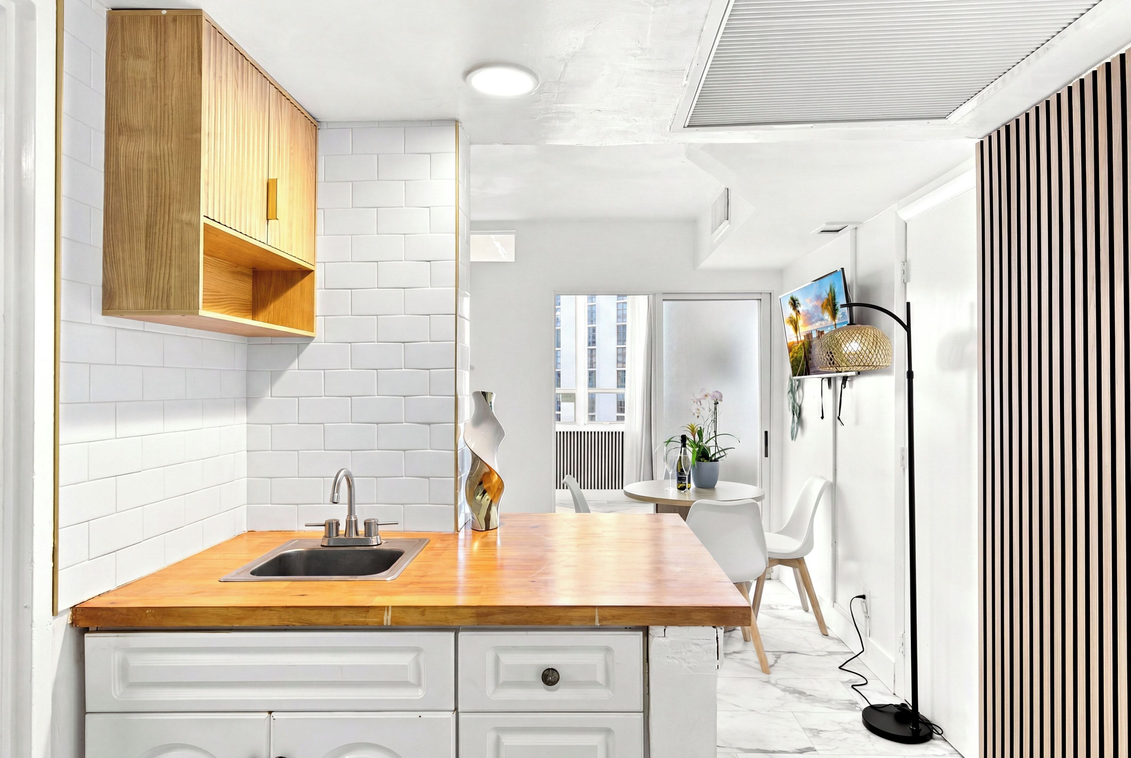 Una cocina moderna con azulejos tipo metro blancos, armarios de madera y encimera de madera.