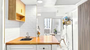 Una cocina moderna con azulejos tipo metro blancos, armarios de madera y encimera de madera.