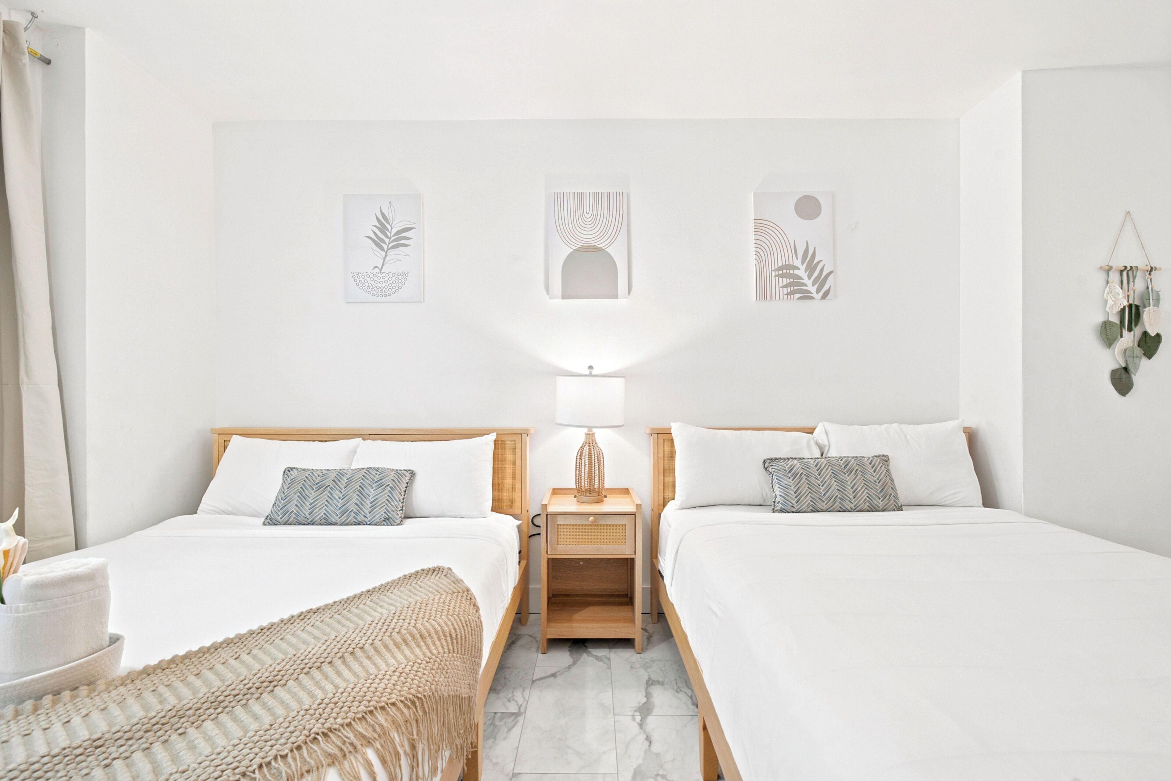 Une chambre double avec deux lits, une table de chevet avec une lampe et des œuvres d’art murales.