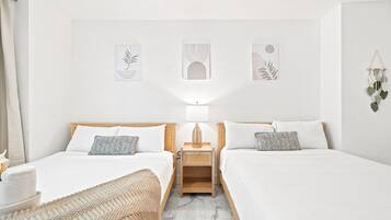 Quarto duplo com duas camas, uma mesa de cabeceira com luminária e decoração nas paredes.
