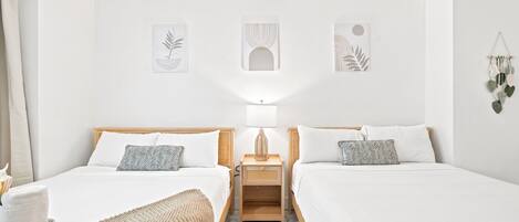 Une chambre double avec deux lits, une table de chevet avec une lampe et des œuvres d’art murales.