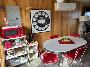 A compact kitchen with a microwave, coffee maker, and a fruit bowl on a table.