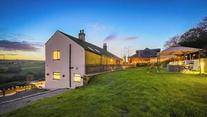 Une maison à deux étages, à l’extérieur blanc, dotée d’un balcon et entourée d’une pelouse bien entretenue et d’une allée pavée.