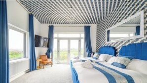 Une chambre dotée d’un grand lit, d’une télévision et offrant une vue sur l’extérieur.