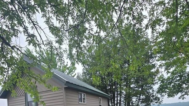 A cabin with a wooden deck, a hose, and a dock extending into a lake. - Popeye and Grammy’s Lookout Point: Cozy Lakeside Cabin for Two (Cornell)