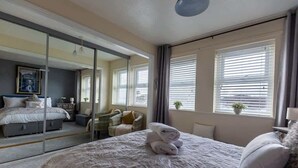 Un dormitorio con una cama grande, un espejo, un escritorio y una silla.