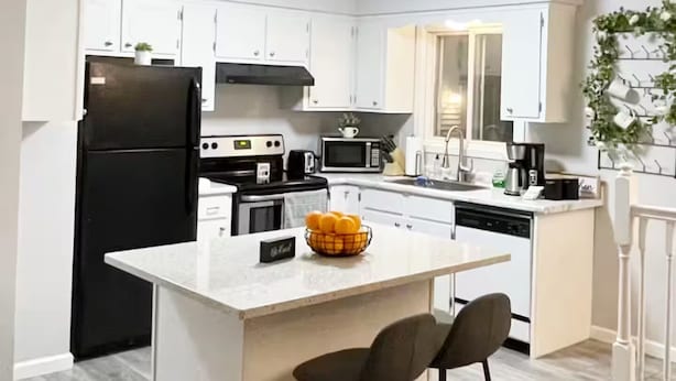 A modern kitchen with white cabinets, a black refrigerator, a microwave, and a coffee maker. - Home in Rochester-Mayo Clinic (Rochester)