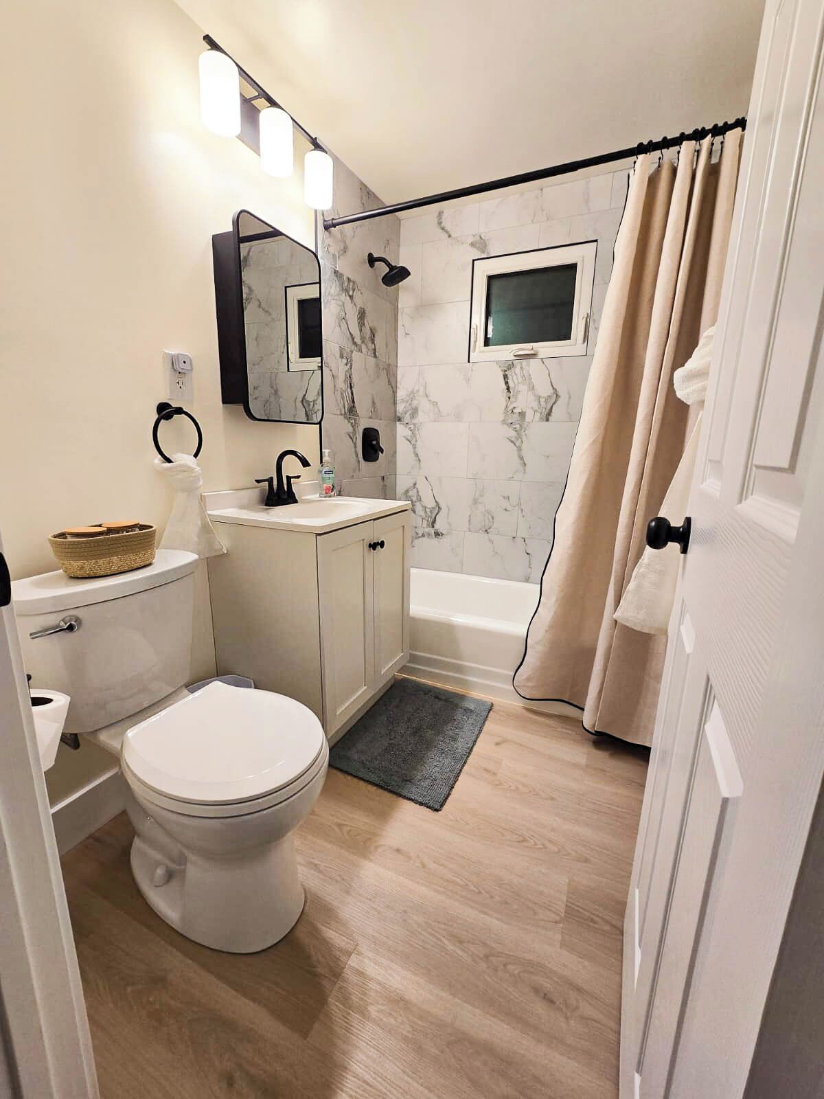 Ein Badezimmer mit Toilette, Waschbecken, Spiegel und Dusche.