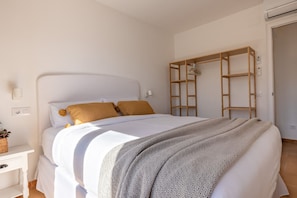 A bedroom with a bed, a wooden ladder shelf, a white nightstand, and a wall socket. - Farigola house with communal pool (L'Escala)