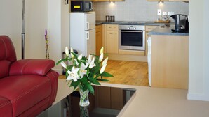 Une cuisine moderne avec des meubles en bois, un four en acier inoxydable et un four à micro-ondes. On y trouve une table à manger avec un vase de fleurs au premier plan.