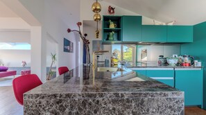 A modern kitchen with a marble island, a red chair, and teal cabinetry. - An art nest between Cinque Terre and Versilia-two unique territories. (Liguria)