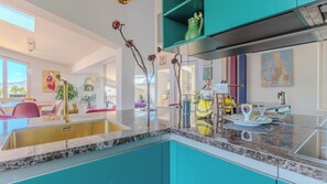 Una cucina moderna con un piano di lavoro in marmo, mobili color verde acqua e una scultura decorativa.