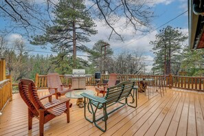 A wooden deck with outdoor furniture, a grill, and a view of trees. - Renovated Moonridge Cabin w/ Hot Tub & Lake Views! (Big Bear)