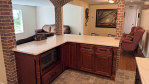 A kitchen with a marble countertop, dark wooden cabinets, and a brick archway.
