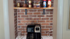 A coffee station with a coffee maker, a fruit tea sampler, and coffee creamer.