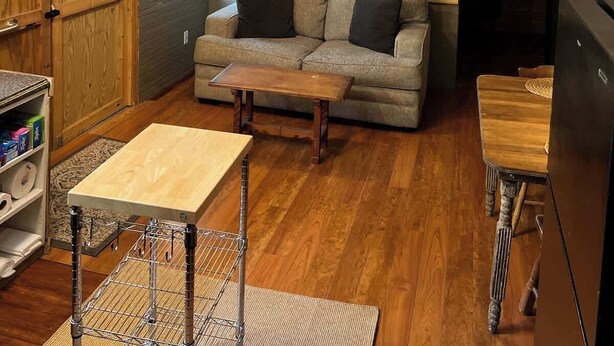Un accogliente spazio abitativo in stile loft con pavimento in legno, un divano, un tavolino da caffè e una ventola a soffitto.