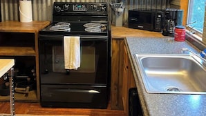Una cucina compatta con fornello, lavello e pensili in legno.