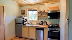 Ett kompakt kök med träskåp, en inbyggd ugn, en diskmaskin och en kaffebryggare.