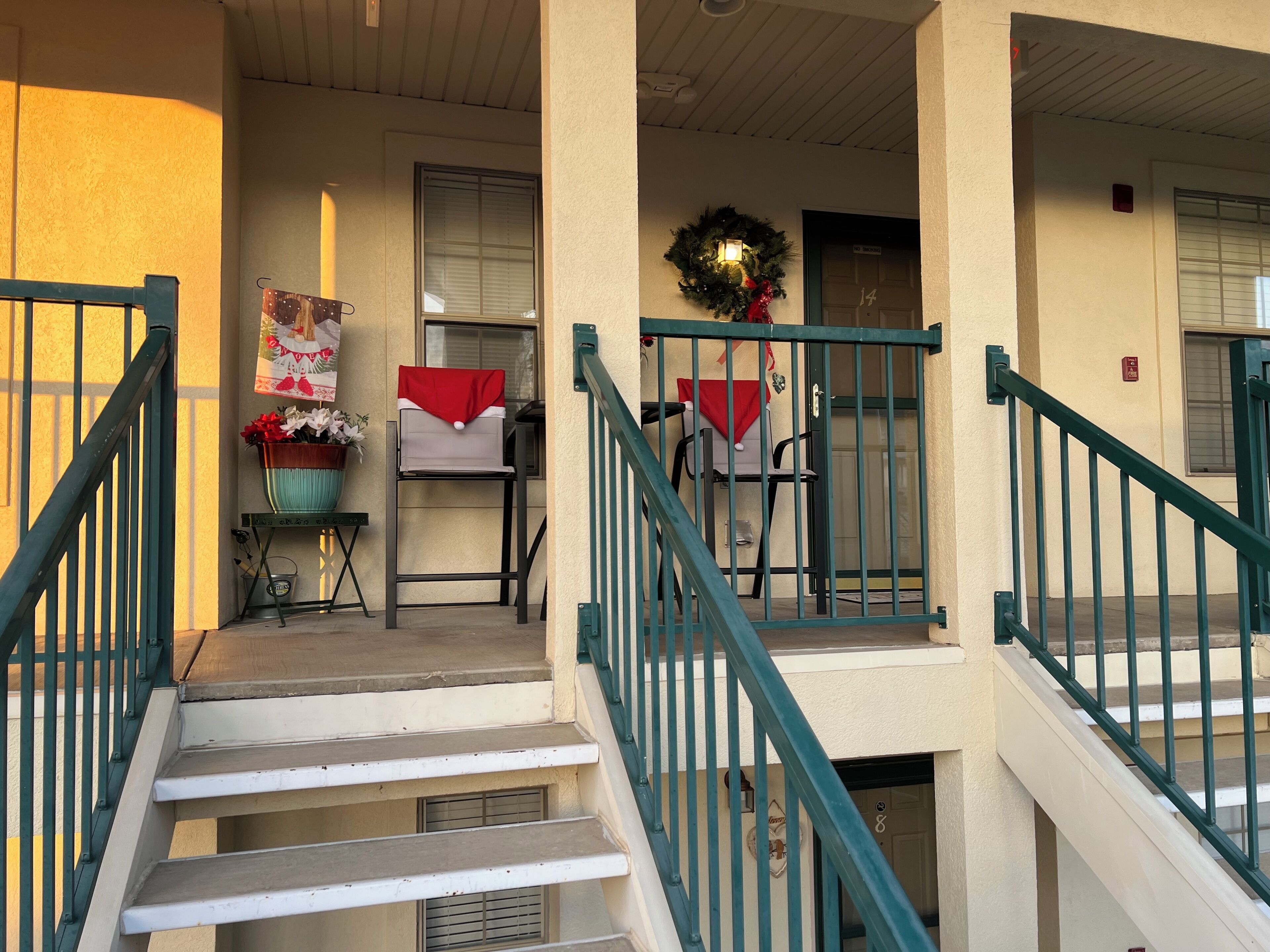 A building entrance with a staircase, a door marked '14', and a wreath on the wall.