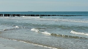 A beach with waves and a wooden jetty. - Vacation park chalet near the beach, modern, cozy and well furnished. (Oostkapelle)