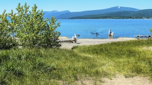 Vista del lago con una mesa de picnic y un banco, rodeado de césped y árboles.