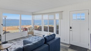 A room with large windows, a white door, and a blue sofa. - The Harrington Hideaway (Coupeville)