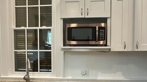 A kitchen with white cabinets, a stainless steel sink, a microwave, and a window with blinds. - Cozy 1-bedroom apartment in adorable New Orleana with AC (New Orleana)