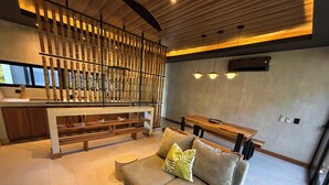Una sala de estar moderna con sofá, banca de madera y un panel decorativo en la pared.