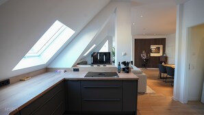 Une cuisine moderne dotée d’une verrière, d’une cuisinière encastrée et d’un coin repas avec une table et des chaises.