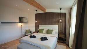Une chambre moderne avec un grand lit, une chaise, une table de chevet et un luminaire fixé au mur.